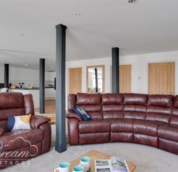 A living room with brown leather sofas and wooden doors at Old Coastguard Apartment 2 in Weymouth