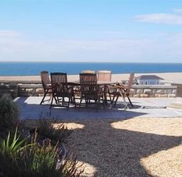 An outdoor patio with a table and six chairs overlooking the ocean at The Old Portland Courthouse in Portland