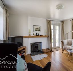 A living room with a fireplace a television curtains and seating at The Old Reading Room in Langton Herring