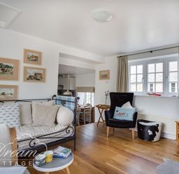 A sitting area with a metal framed sofa and black armchair near windows at The Old Reading Room in Langton Herring
