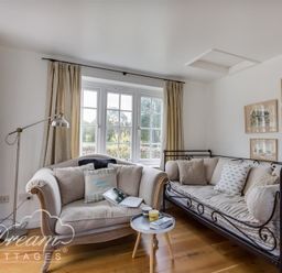 A living room with two sofas a small round table and paintings on the wall at The Old Reading Room in Langton Herring