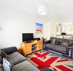 A living room with two sofas a television on a wooden stand and a Union Jack rug at Olympic Cottage in Portland