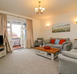 A living room with sofas cushions coffee table tv and door to balcony at Ocean Watch 1 in Greenhill