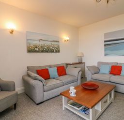 A living room with two sofas and an armchair a wooden coffee table and wall art at Ocean Watch 1 in Greenhill