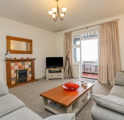 A living room with sofas a wooden coffee table a fireplace and a television at Ocean Watch 1 in Greenhill