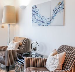A living room with striped armchairs and a lamp at Estuary View in Kingsbridge