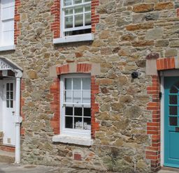 Stone wall with two doors and two windows on a street at 14a Courtenay Street in Salcombe