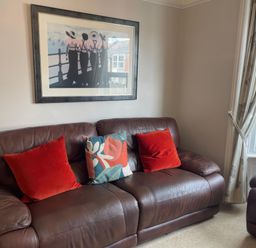 A living room with a brown sofa and wall art at Pedaller's Cottage, Weymouth