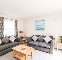 A living room with two grey sofas and a wooden coffee table with books at The Pines in Weymouth