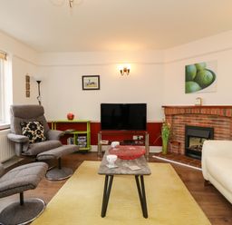 A living room with two gray recliner chairs a white sofa a TV on a stand and a fireplace at Poppies Brewers Quay Harbour
