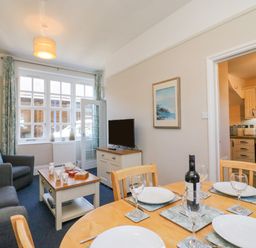 A dining table set with plates and wine bottle next to a living area with sofas and a TV at Reaver Brewers Quay harbour