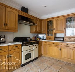 A kitchen with wooden cabinets a stove a microwave a toaster and a kettle at Redcliff View Lodge in Weymouth