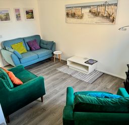 A living room with green and blue sofas a white coffee table and a television at Rockpools in Weymouth