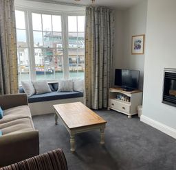 A living room with a sofa, television, and coffee table at Safe Harbour in Brewers Quay harbour