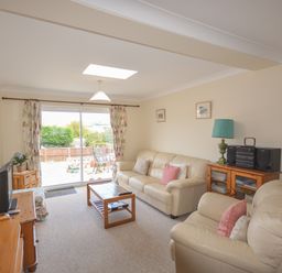 A living room with leather sofas a wooden coffee table and a sliding glass door leading outside at Sanjernin Swanage