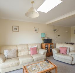 A living room with cream leather sofas a wooden coffee table a side cabinet with a turquoise lamp and a stereo at Sanjernin in Swanage