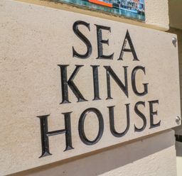 A stone sign with the text sea king house attached to a building wall at Cove Castle