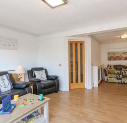 A living room with black leather sofas and a wooden coffee table with a game set at Sea Pebbles in Weymouth