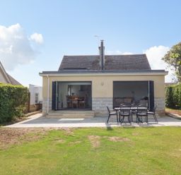 A backyard with patio furniture and open doors of a house at Shipton Hill View in Shipton Gorge