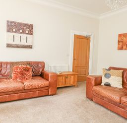 A living room with two brown leather sofas a wooden door and a wooden chest at Sea Star in Weymouth