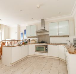 A kitchen with white cabinets a stove microwave and a dining table with chairs at Sea Star in Weymouth