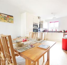 A kitchen and dining area with a wooden dining table and chairs and white kitchen cabinets at St Johns View in Portland