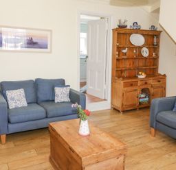 A living room with blue sofas wooden chest coffee table and wooden cabinet at Studland Cottage in Studland