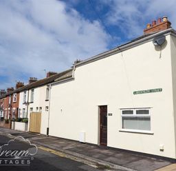 A row of terraced houses along a street with a street sign reading brownlow street at Sunny Days in Weymouth