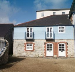 A stone and blue wooden house exterior with two white doors and windows at Upsidedown House in Brewers Quay Harbour