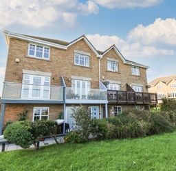 A brick residential building with balconies and a grassy lawn at Waters Edge in Wyke Regis