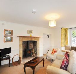 A living room with a fireplace and wood stove a sofa and armchair a coffee table a window seat with cushions and yellow curtains at Warmwell Lodge in Warmwell