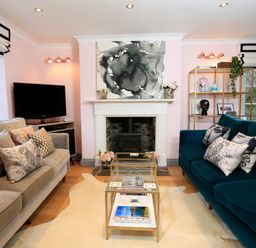 A living room with two sofas a glass coffee table and a fireplace at 16 Courtenay Street in Salcombe