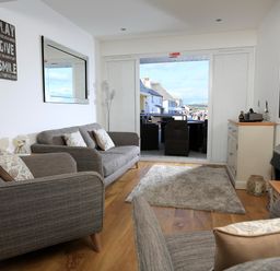 A living room with sofas a rug a wall mirror and a cabinet with a TV at 1 At The Beach in Torcross