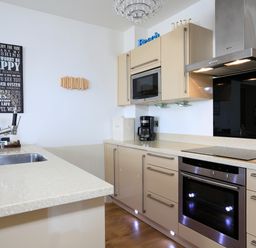 A kitchen with beige cabinets stainless steel oven and microwave coffee maker and sink with a modern faucet at 1 At The Beach in Torcross