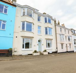 A street view of multi story buildings including a cream building with an arched entrance and a blue building at 3 Dartview Dartmouth