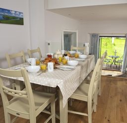 A dining area with a table set for breakfast including croissants orange juice and bowls at 3 Eddystone Row in Salcombe