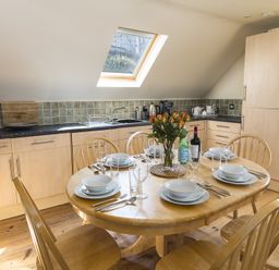 A kitchen with a wooden dining table set for six and a skylight window at 4 Armada House in Hope Cove