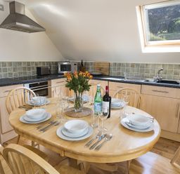 A kitchen with a round wooden dining table set for six under a skylight at 4 Armada House in Hope Cove