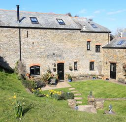A stone house with a garden and daffodils in the lawn at Cowslip Cottage in Frogmore