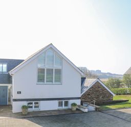 A white house with a blue door and large windows with shutters at Sea Peep in Thurlestone