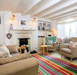 A living room with armchairs a sofa a fireplace and a multicolored striped rug at Bow Cottage in East Portlemouth