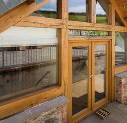 Exterior wooden framed glass doors and windows of a building with stone and brick walls at Butterwell Barn in Dartmouth