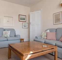A living room with two blue sofas wooden coffee table and framed pictures on walls at Cottage View in Hope Cove