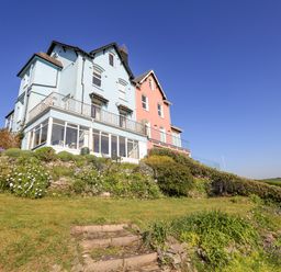 A blue and pink house on a hill with garden and stone steps at Edinburgh House in Salcombe
