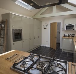 A kitchen with a gas stove on a wooden countertop cabinets oven microwave and a wooden door at Gooder House in Dartmouth