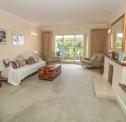 A living room with a sofa and armchairs a wooden coffee table and a fireplace at The Hoot 16 St Elmo Court in Salcombe