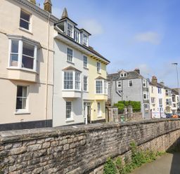 A street with multiple two to three story houses next to a stone wall at Kings View in Dartmouth