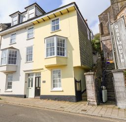 A street view of connected houses with bay windows and a stone stairway beside a building with a dartmouth sign at Kings View in Dartmouth
