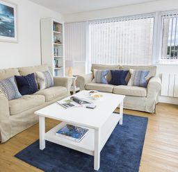 A living room with two beige sofas and a white coffee table on a blue rug at Leeside in Dartmouth