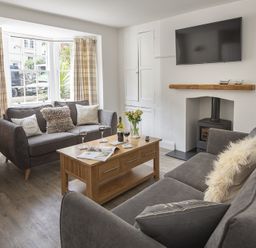 A living room with two gray sofas a wooden coffee table and a wall mounted tv at The Old Wash House in Dartmouth